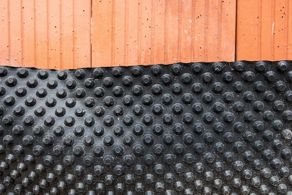 Schwarze Noppenfolie auf roten Ziegeln